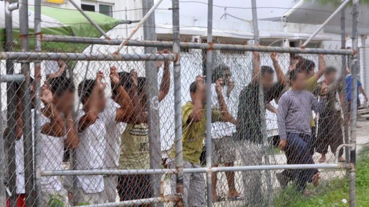 A group of asylum seekers behind a fence at a compound in PNG.