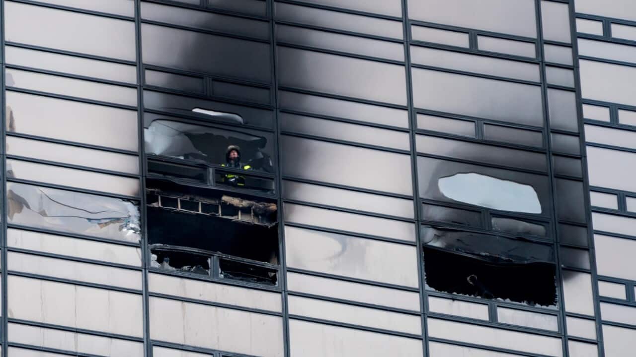 A firefighter looks out from the window of a fire damaged apartment in Trump Tower in New York on Saturday, April 7