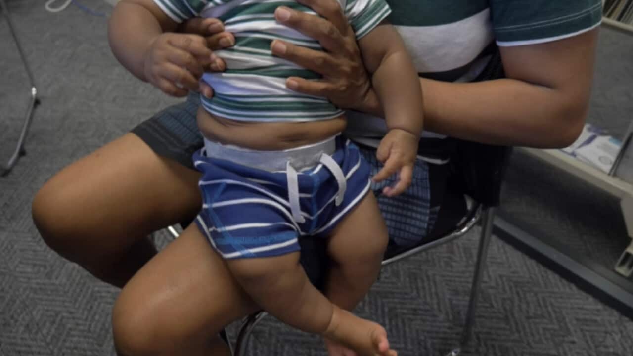 A photo of a woman holding a small boy. Both their heads are out of frame.