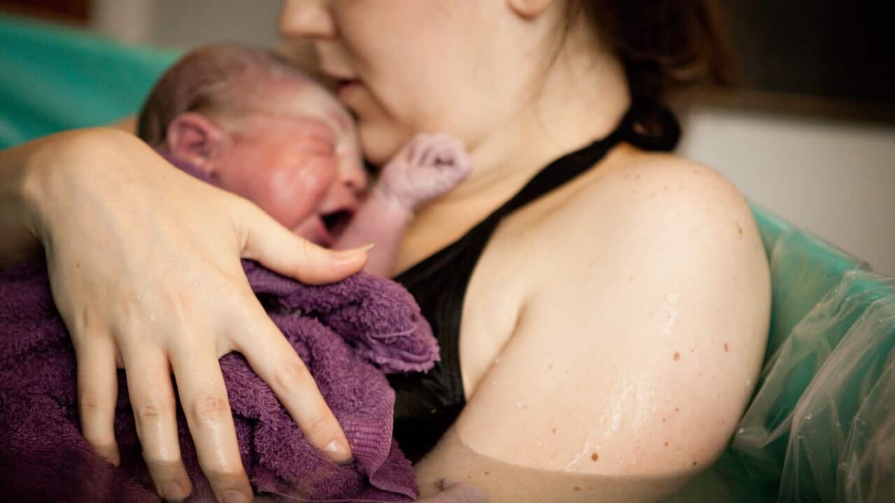 A mother holding her newborn baby in the water of a birthing tub