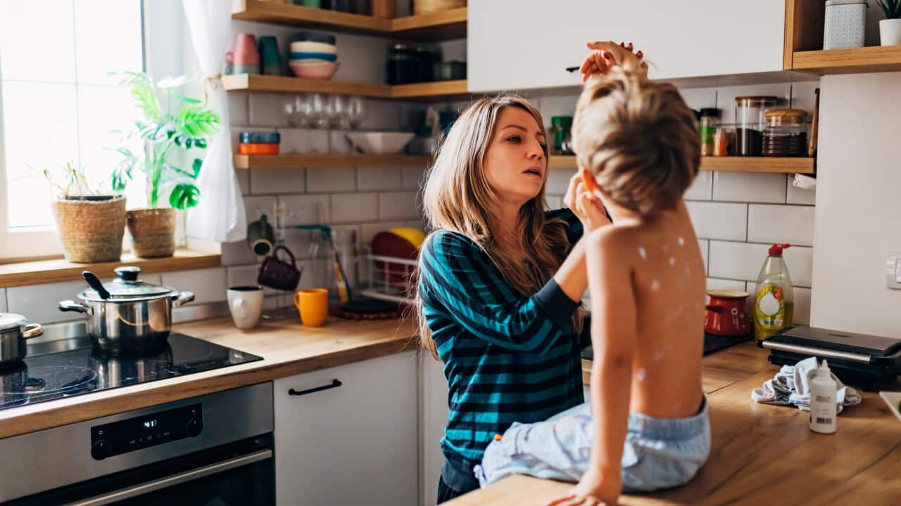 A mother carefully applies chickenpox medicine to her son, making sure to apply the medicine over each polka dot