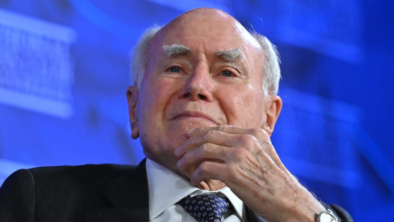 Former Australia prime minister John Howard sits with his left hand cradling his chin.