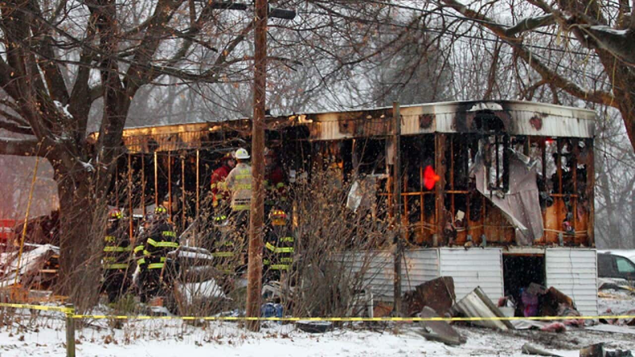 Emergency service crews inspect the scene of a mobile home fire