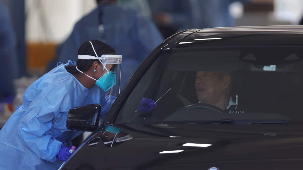 A health staff member is seen administering a PCR test as members of the public queue in their cars at a drive-through COVID-19 testing site at Albert Park, in Melbourne, Thursday, December 30, 2021. Victorian travellers getting tested to cross state bord