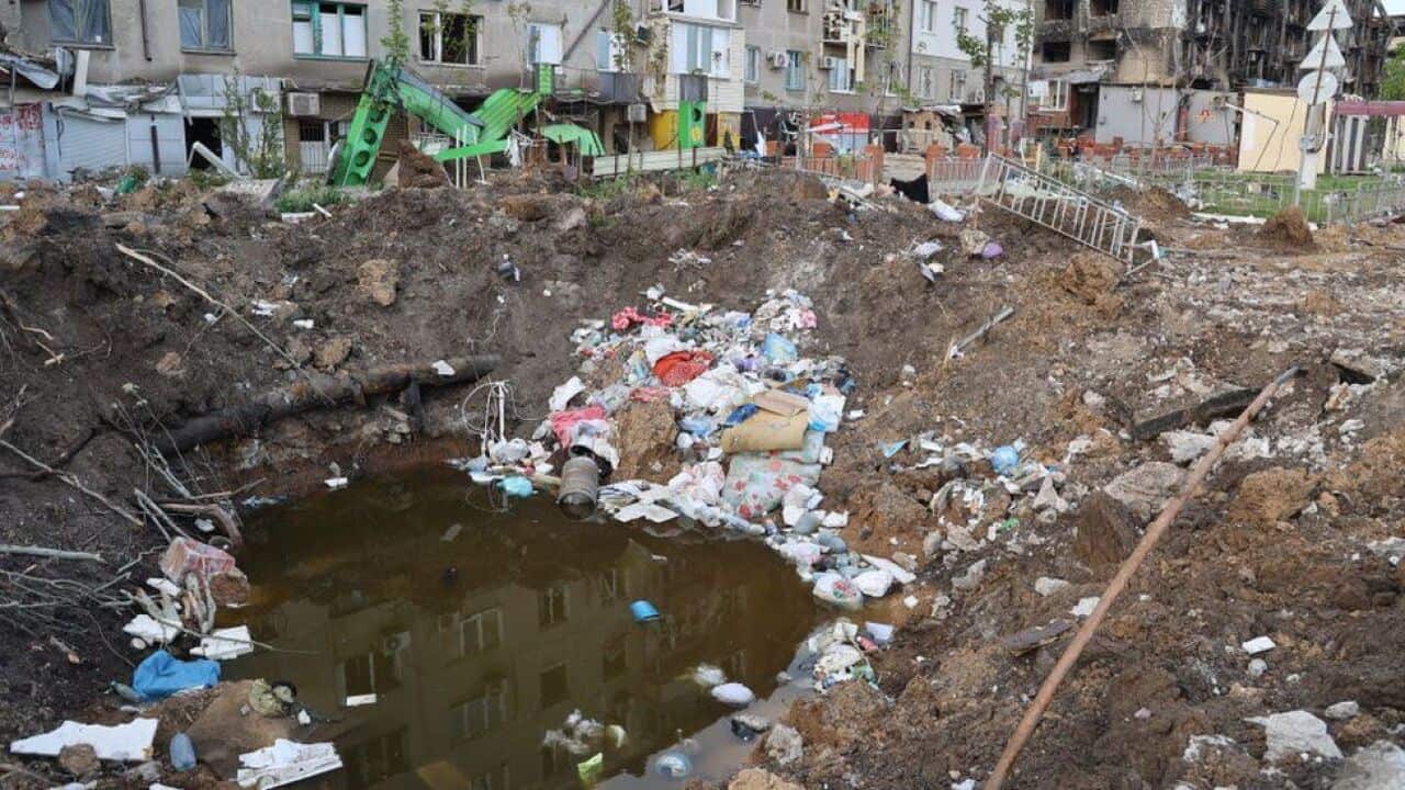 An explosion crater filled with water and rubbish in Mariupol.