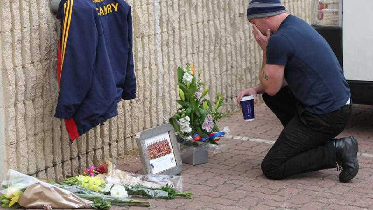 Adelaide Crows Corey Bruce lays flowers at the footballclub headquarters at AAMI stadium, Adelaide after AFL Crows coach Phil Walsh, was found dead after a domestic dispute on Friday, July 3, 2015, at his home in Somerton Park, Adelaide, Australia. 