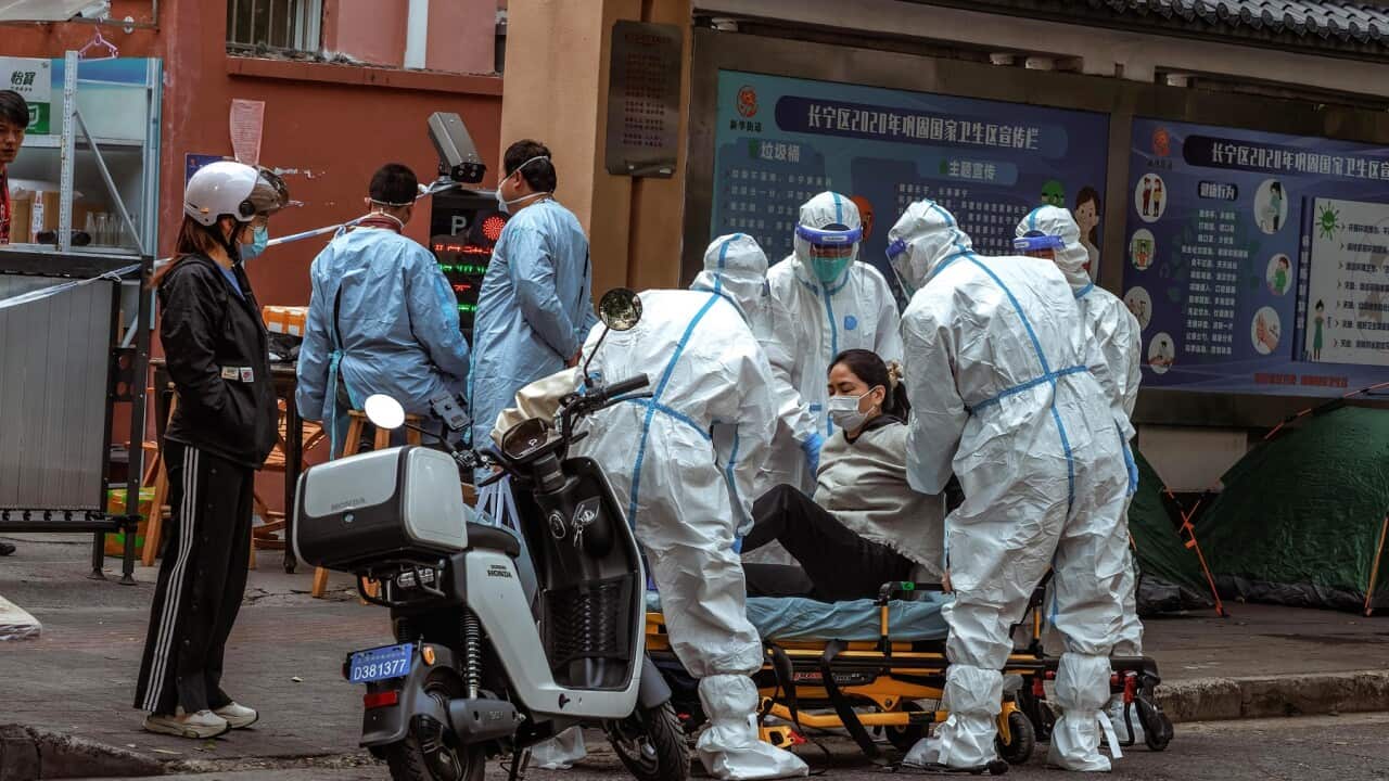 A woman is taken to the hospital by ambulance staff during a Covid-19 lockdown in Shanghai, China in 2022 (AAP)