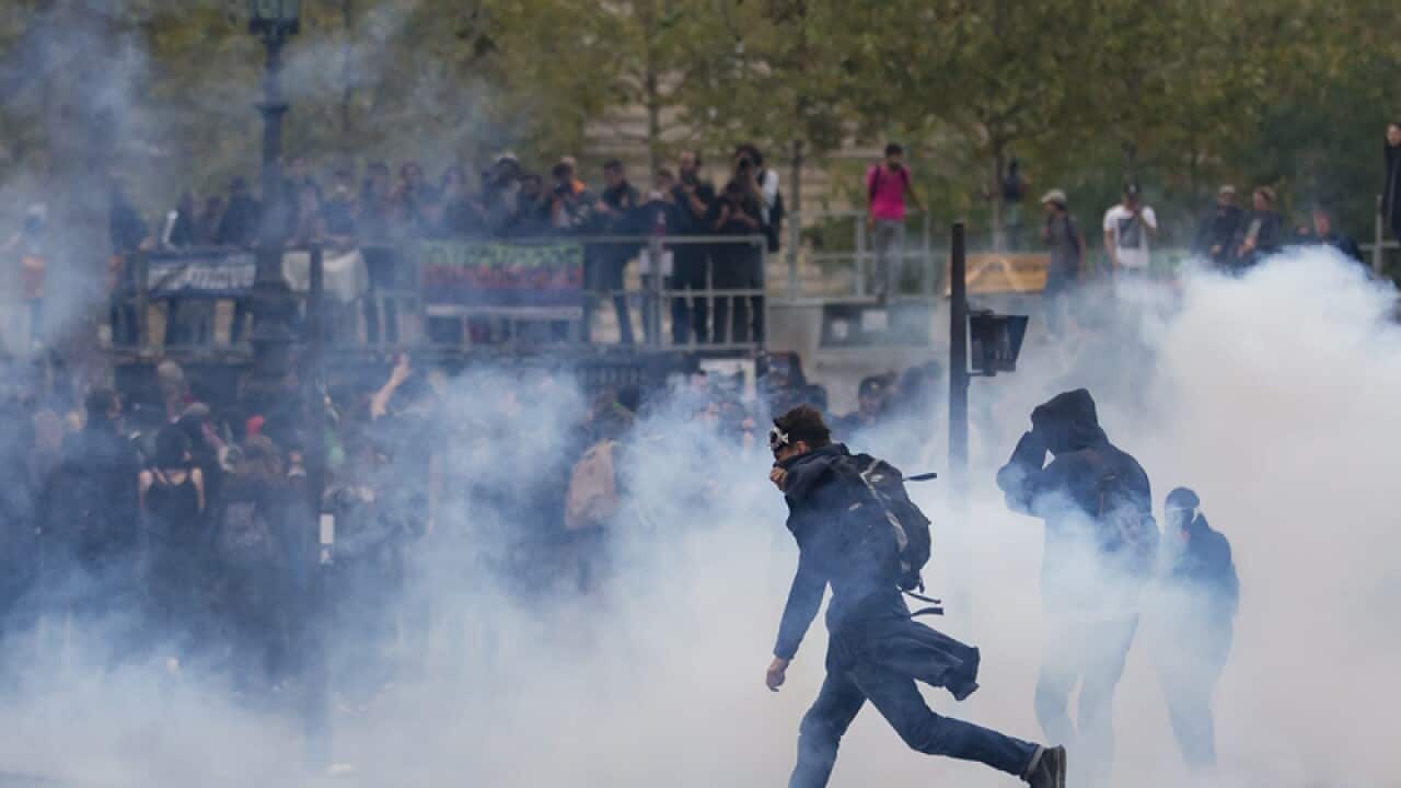 protester kicks back a tear gas canister