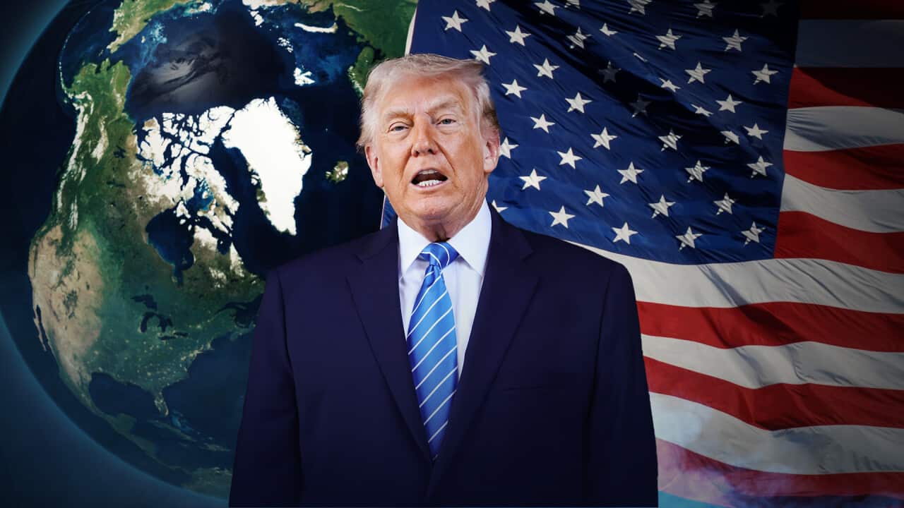 Donald Trump is standing in front of a map showing Greenland and the United States flag.