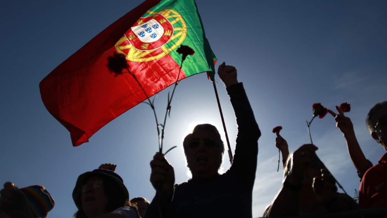 People holding red carnations and a Portuguese flag during May Day