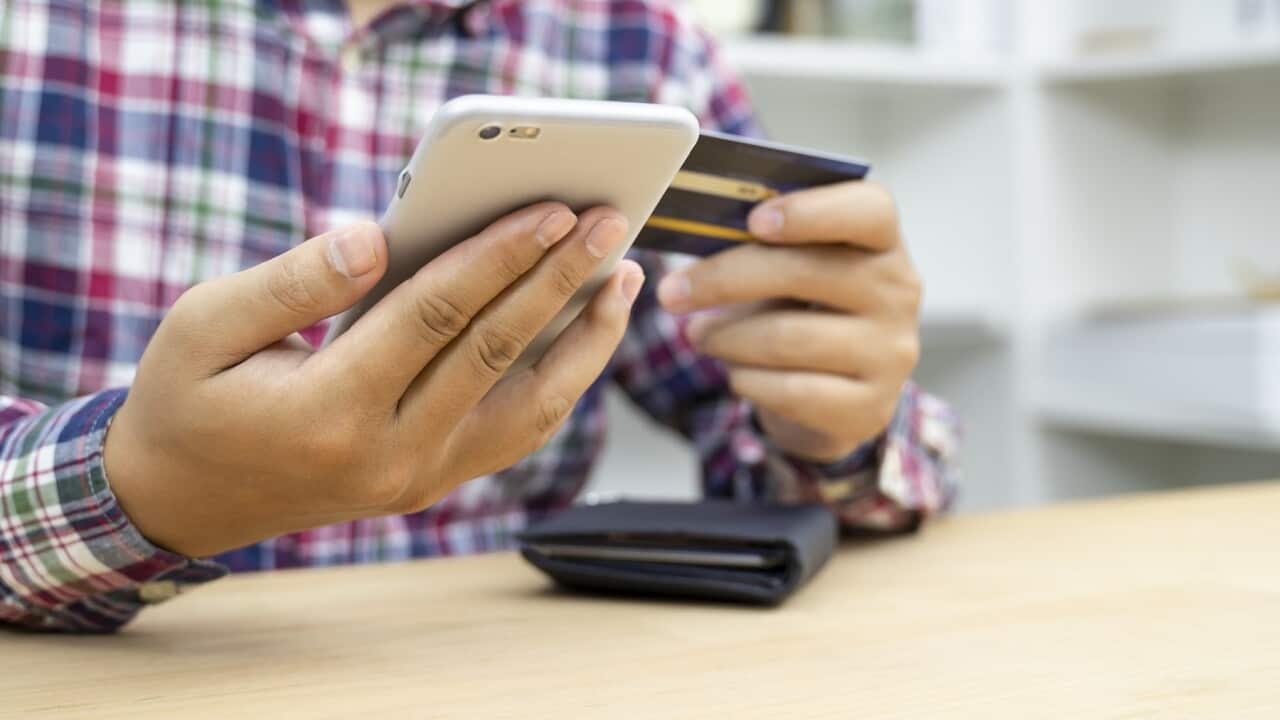 Young man hands holding credit card and using phone
