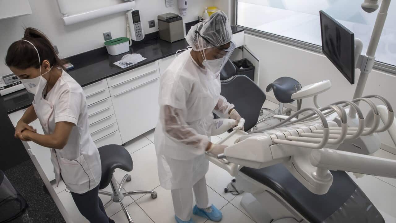 A dentist and her assistant prepare for a dental appointment