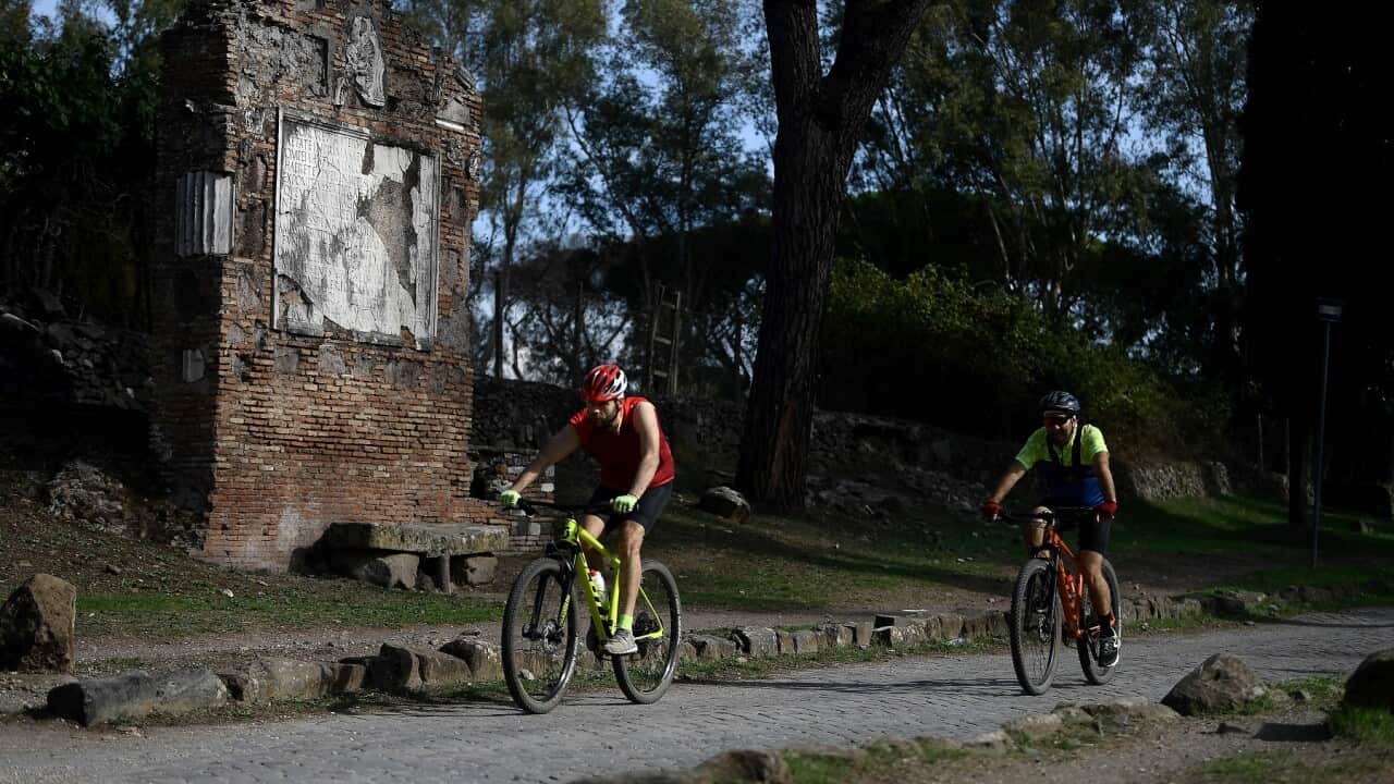 Cyclists ride along the Appian Way.