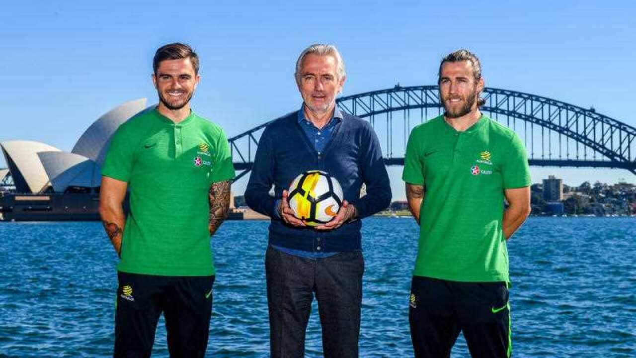 Socceroos Head Coach Bert van Marwijk (centre) with Midfielder Josh Brillante (right) and defender Josh Risdon pose for a photograph on Sydney Harbour in Sydney, Monday, May 7, 2018.