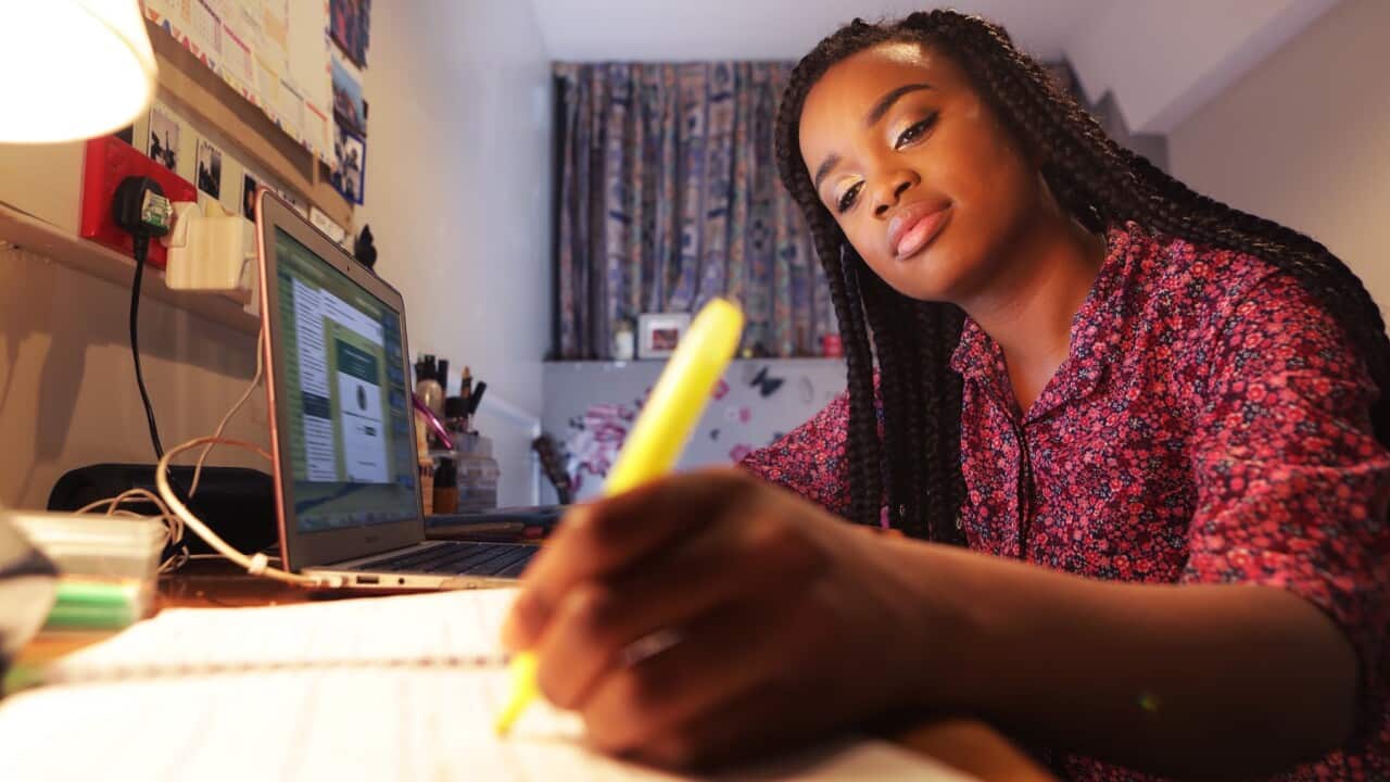 Student working at desk in bedroom at night
