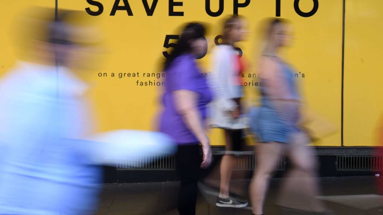 Pedestrians walk past an advertisement outside a department store