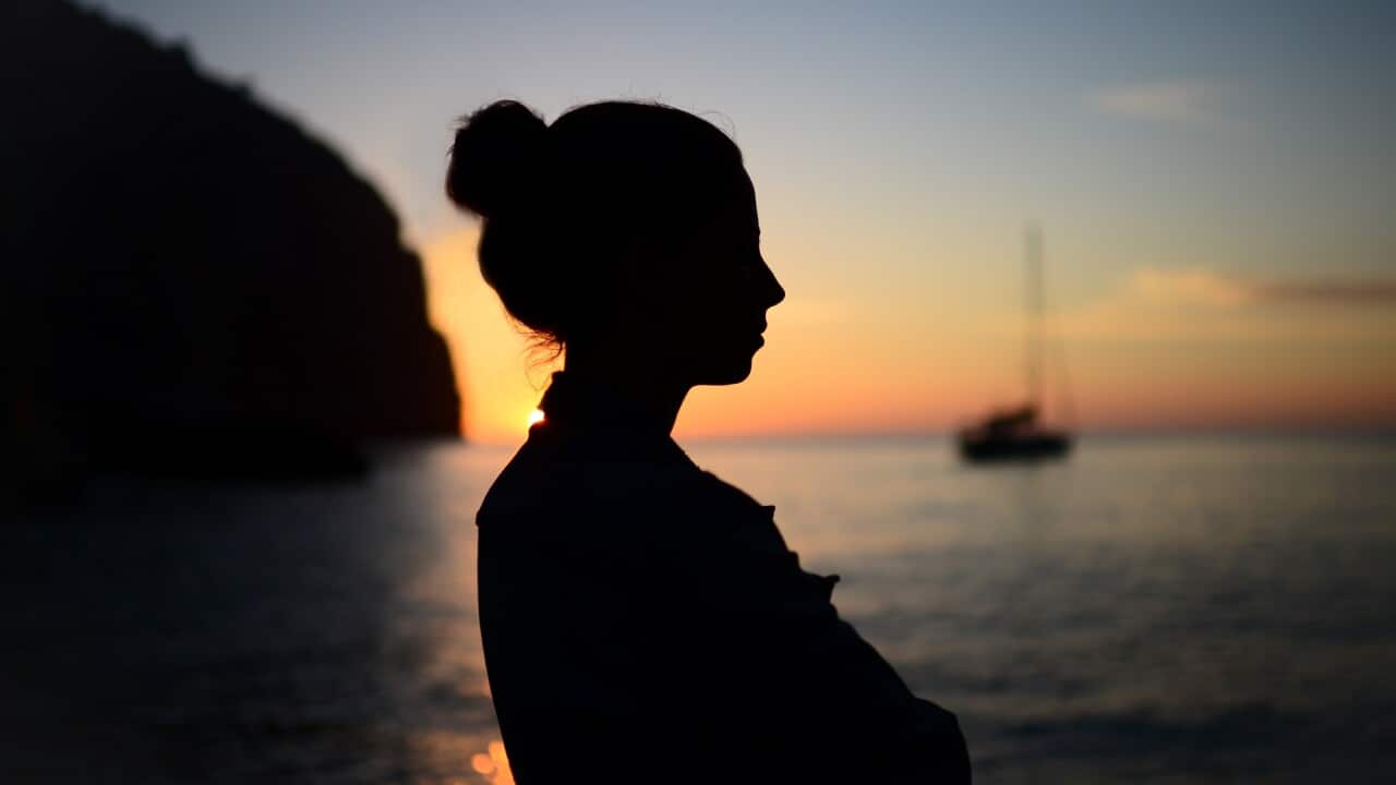 Silhouette of a contemplative young woman enjoying a beautiful sunset