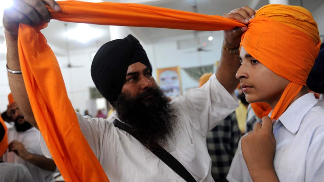 A Sikh boy has a turban tied over his head