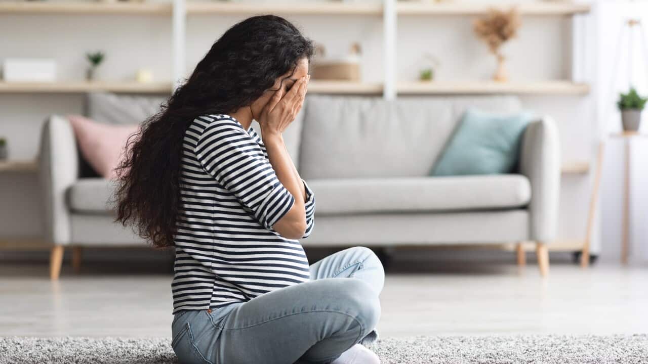 Crying pregnant woman feeling down while staying alone at home