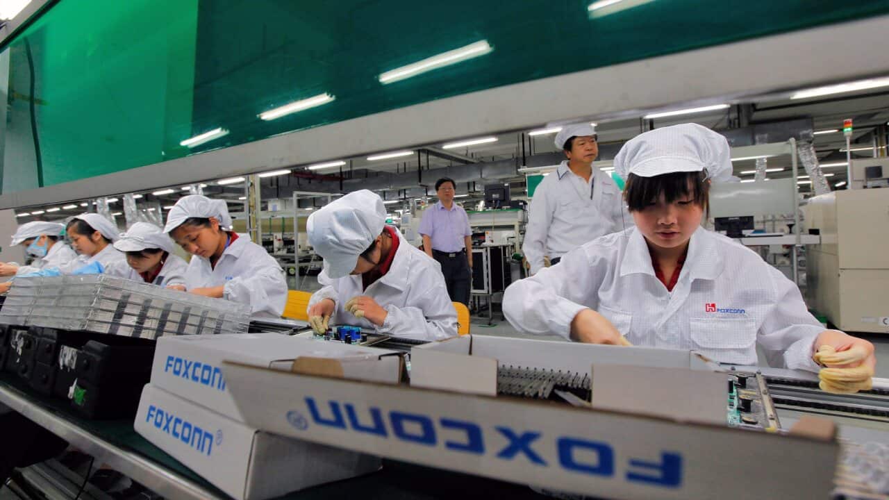 Workers in a factory wearing white uniforms and caps.