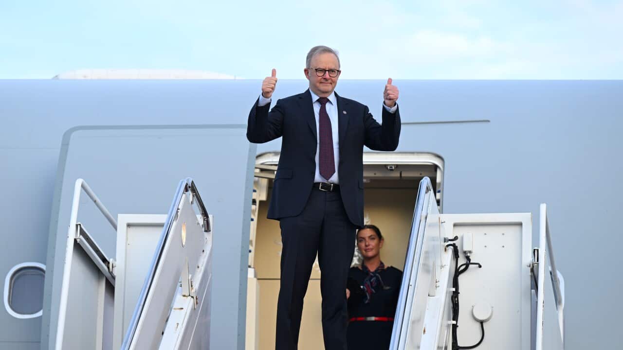 Anthony Albanese on the steps of a plane, giving a double thumbs up.