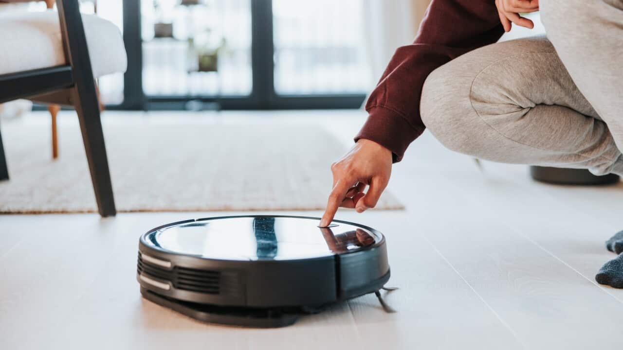 Latin man turning his vacuum robot on