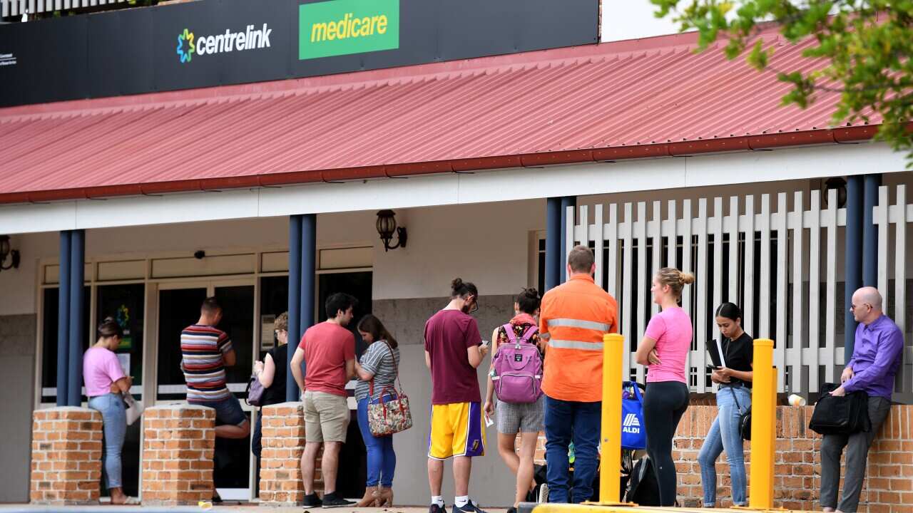 People stand in a long queue outside a Centrelink office.