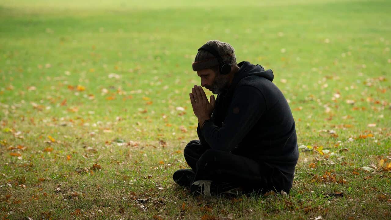 A man prays in Hagley Park, on Deans Avenue, opposite the scene of the Masjid Al Noor mass shooting in Christchurch.