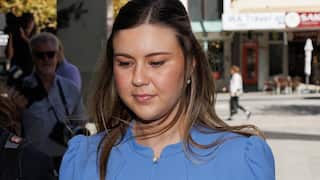 A woman wearing a blue dress looking down on the ground