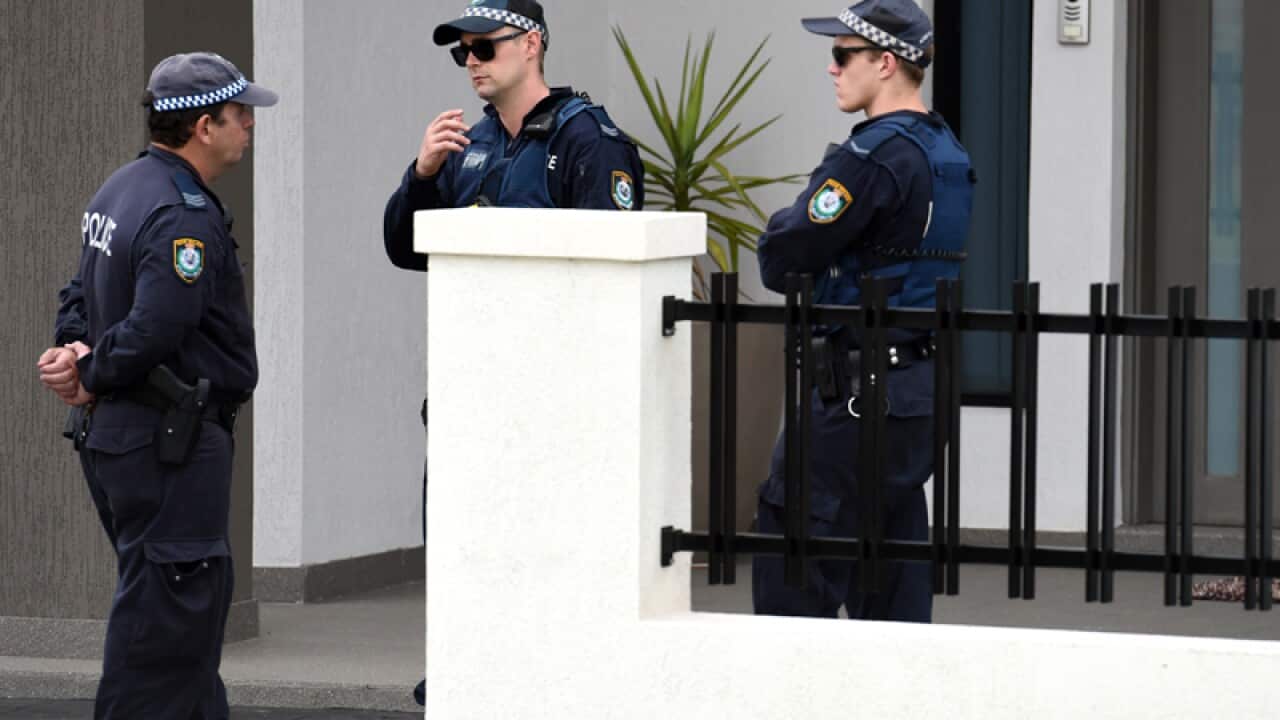 Police officers stand at a property being searched in Sydney