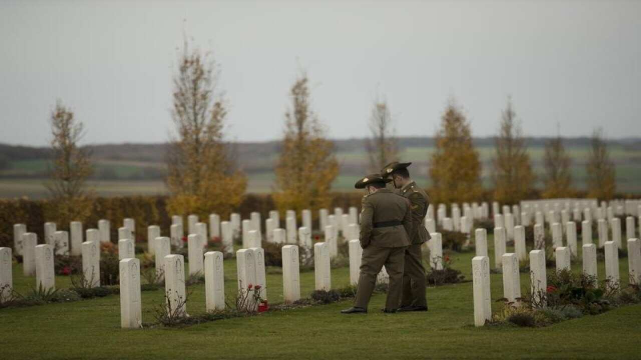 Two soldiers walk along the graves at Villers-Bretonneux