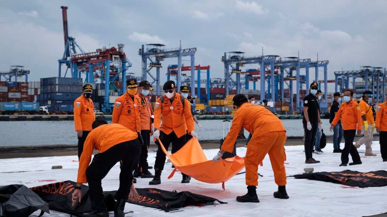 Indonesian SAR workers examining debris and remains from the missing Sriwijaya Air flight SJ 182.