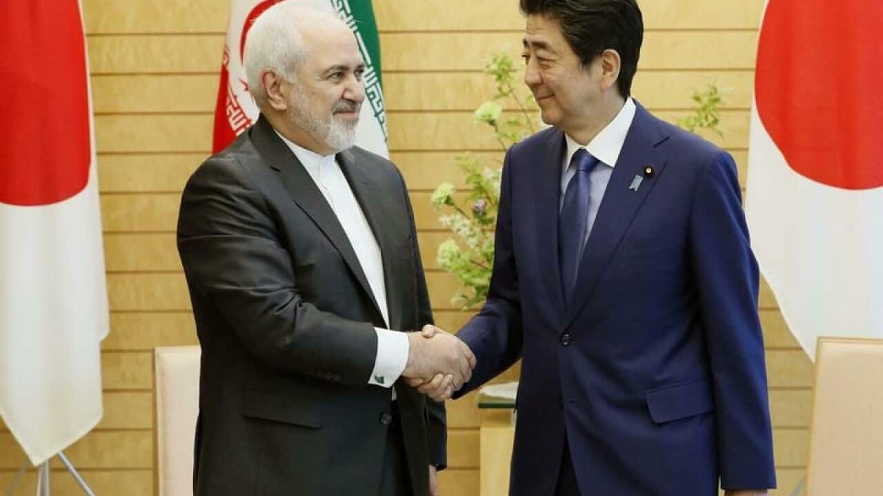Shinzo Abe and Mohammad Javad Zarif shake hands.
