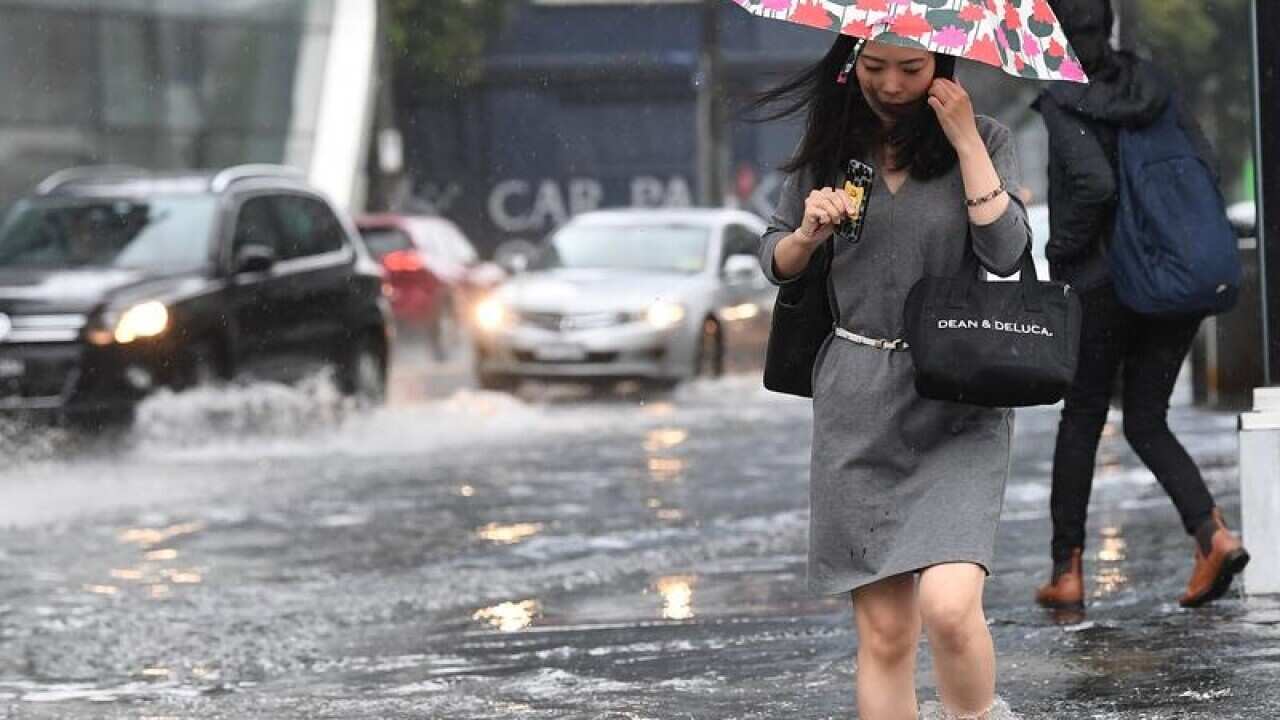 Pedestrians walk through flood waters in South Melbourne.
