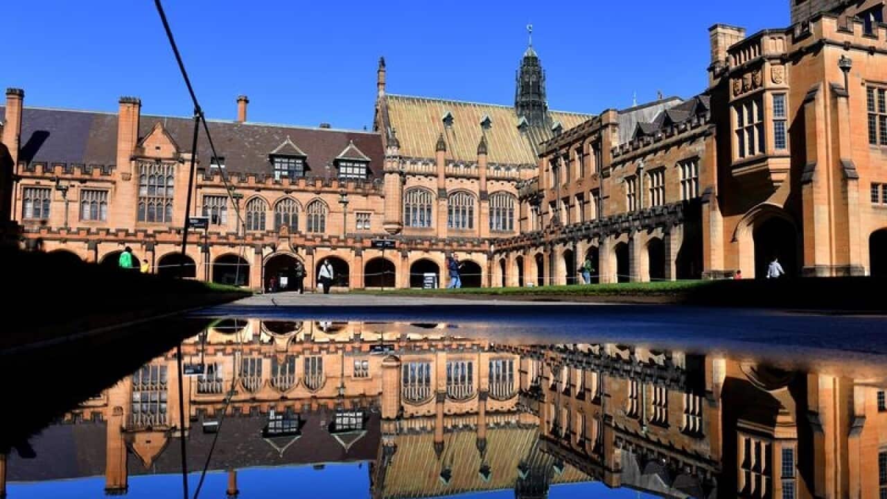 Sydney University quadrangle is seen reflected in a water puddle.