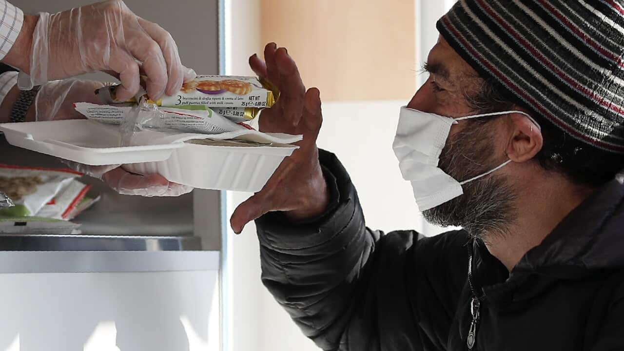 A volunteer services a homeless man some food in Italy.