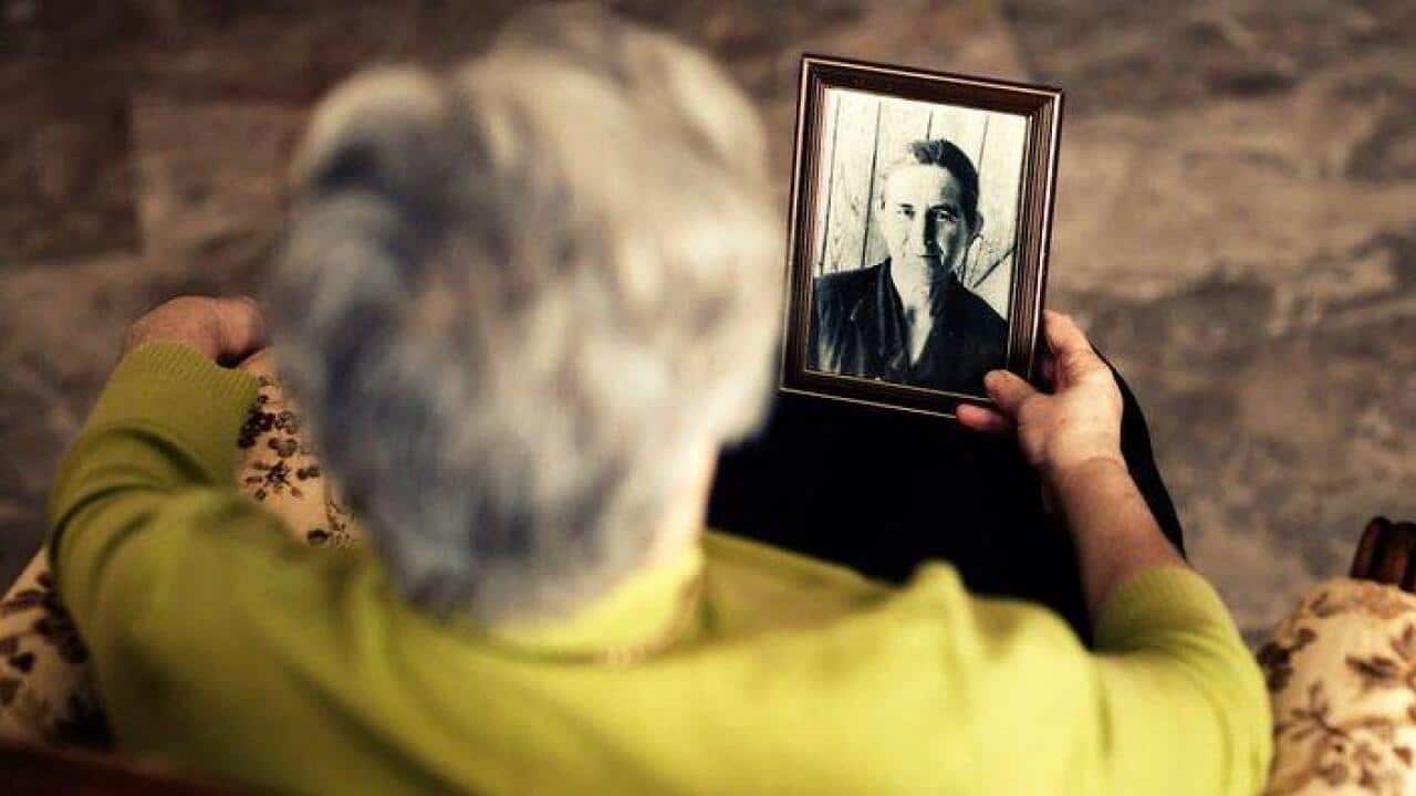 An Old woman looking at her frame photo.