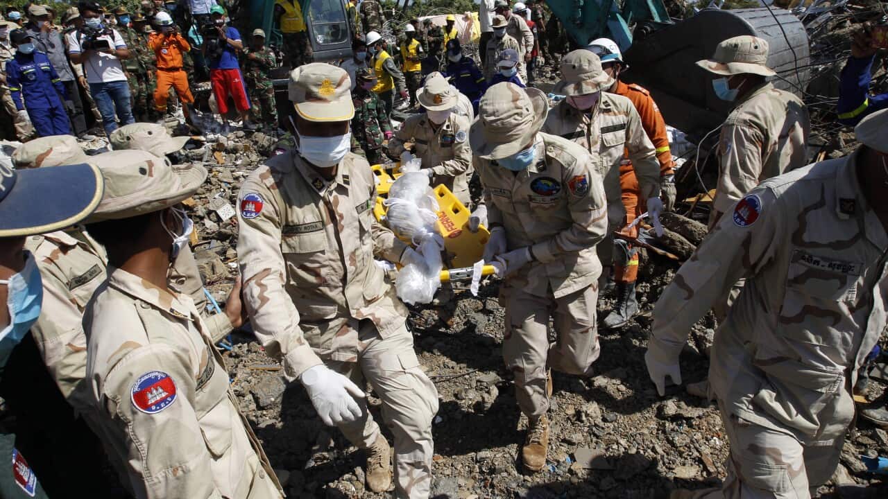 Cambodian rescuers carry the body of a victim out of a collapsed building.