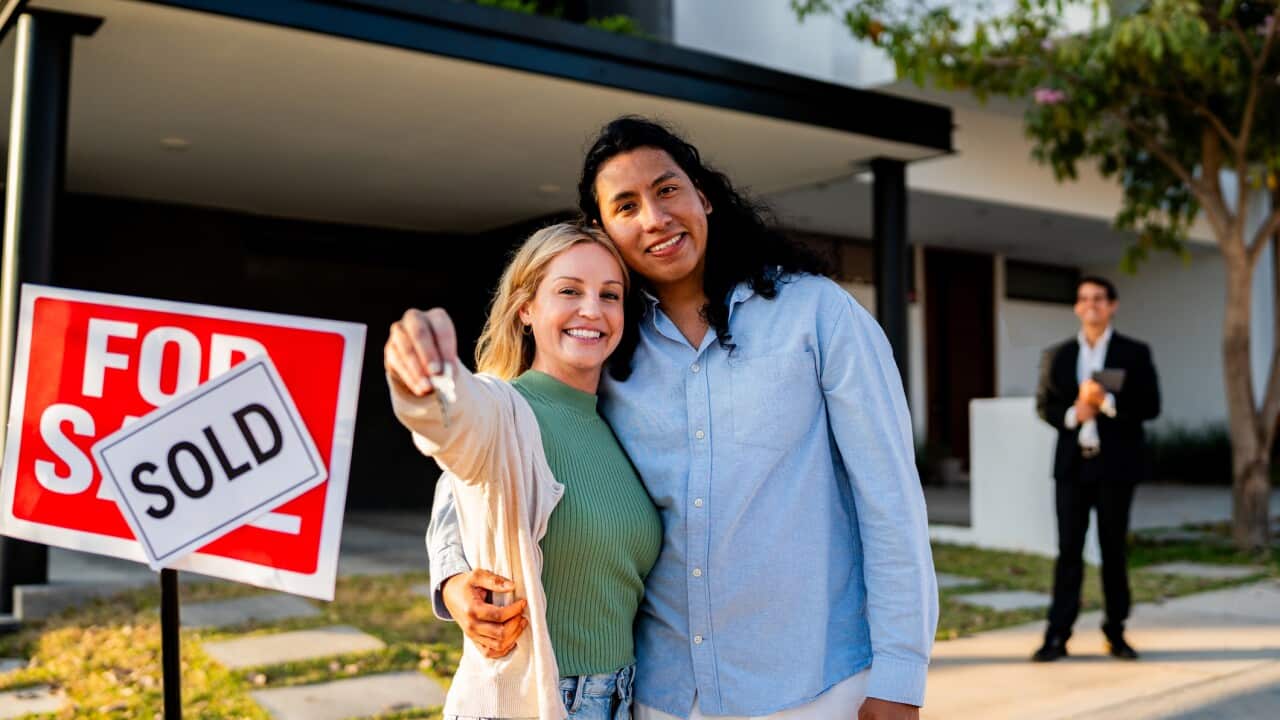 Portrait of couple holding new house key at house yard