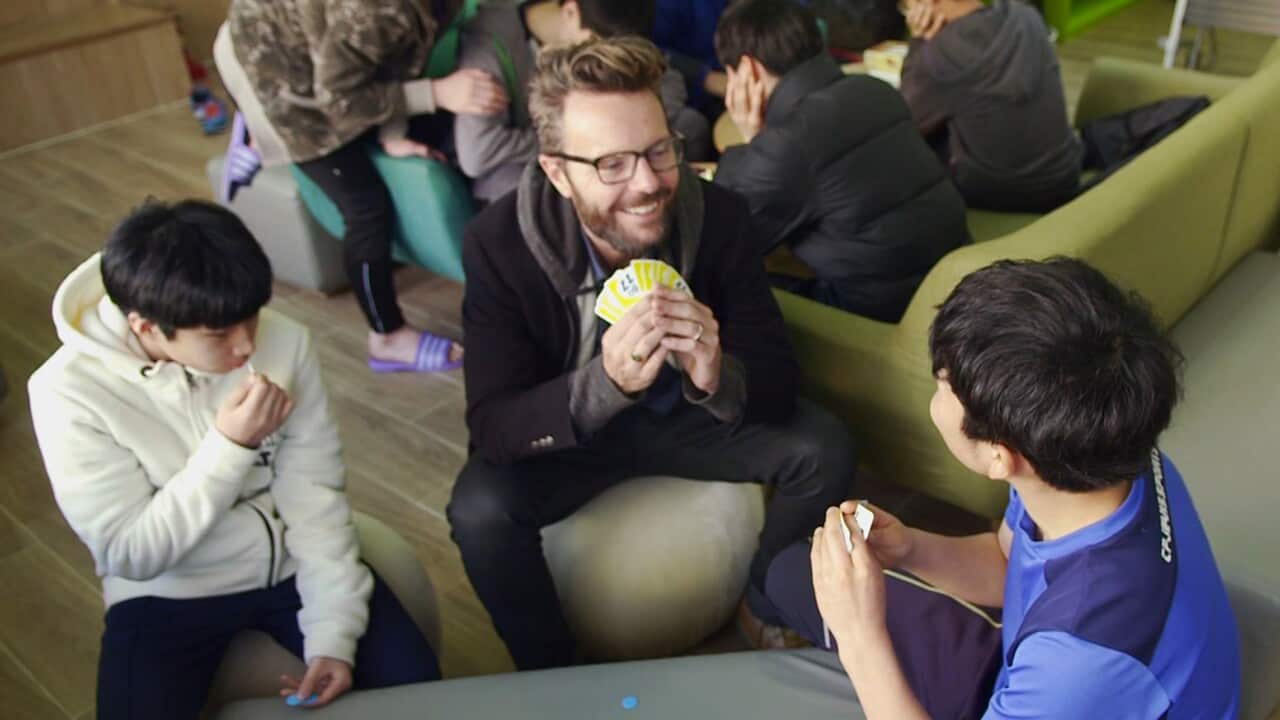 Dean Cornish plays cards with the teenagers at South Korea's 'Dream Village' for internet addicts.