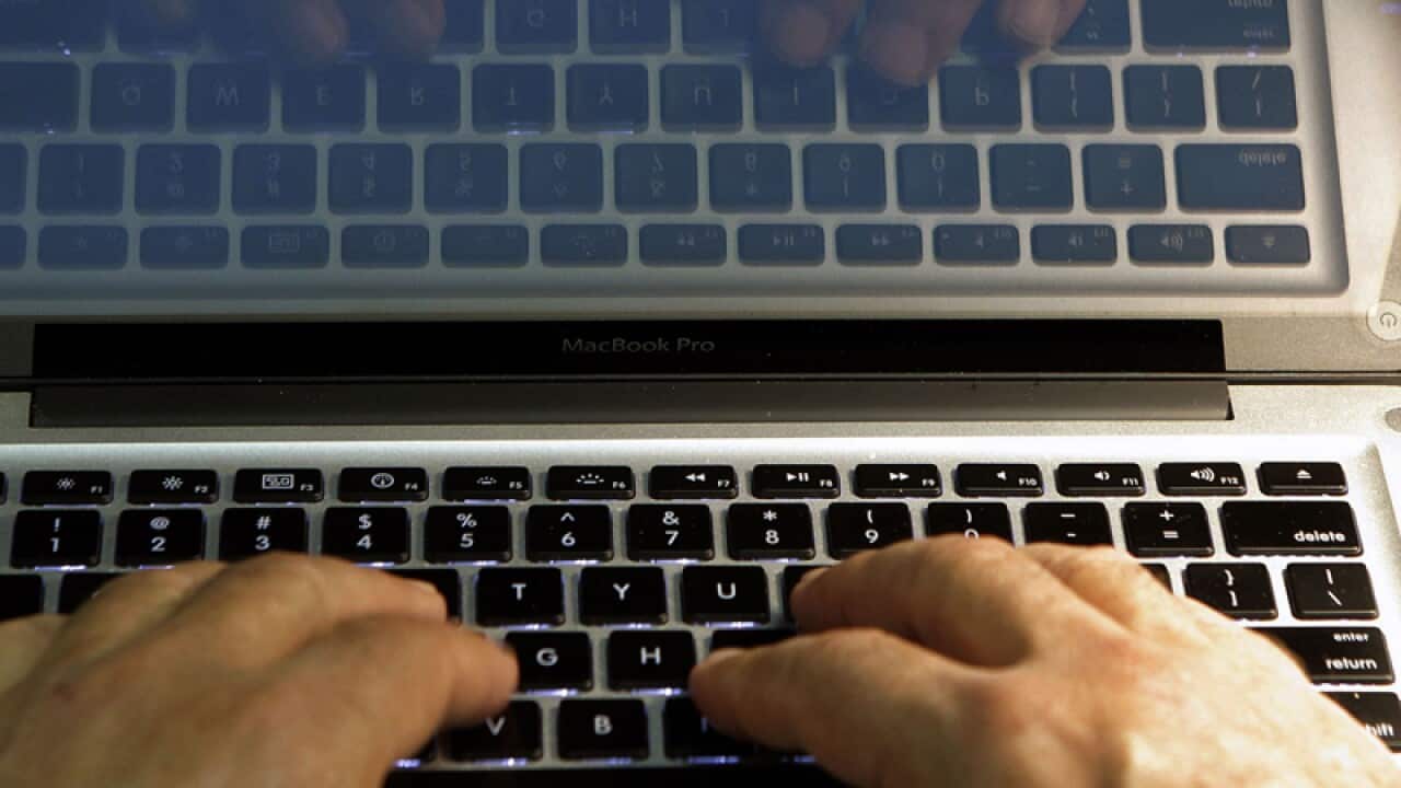 Hands type on a computer keyboard