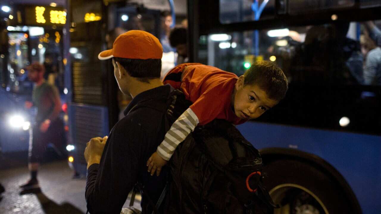 A man carries a child onto a bus provided by Hungarian authorities