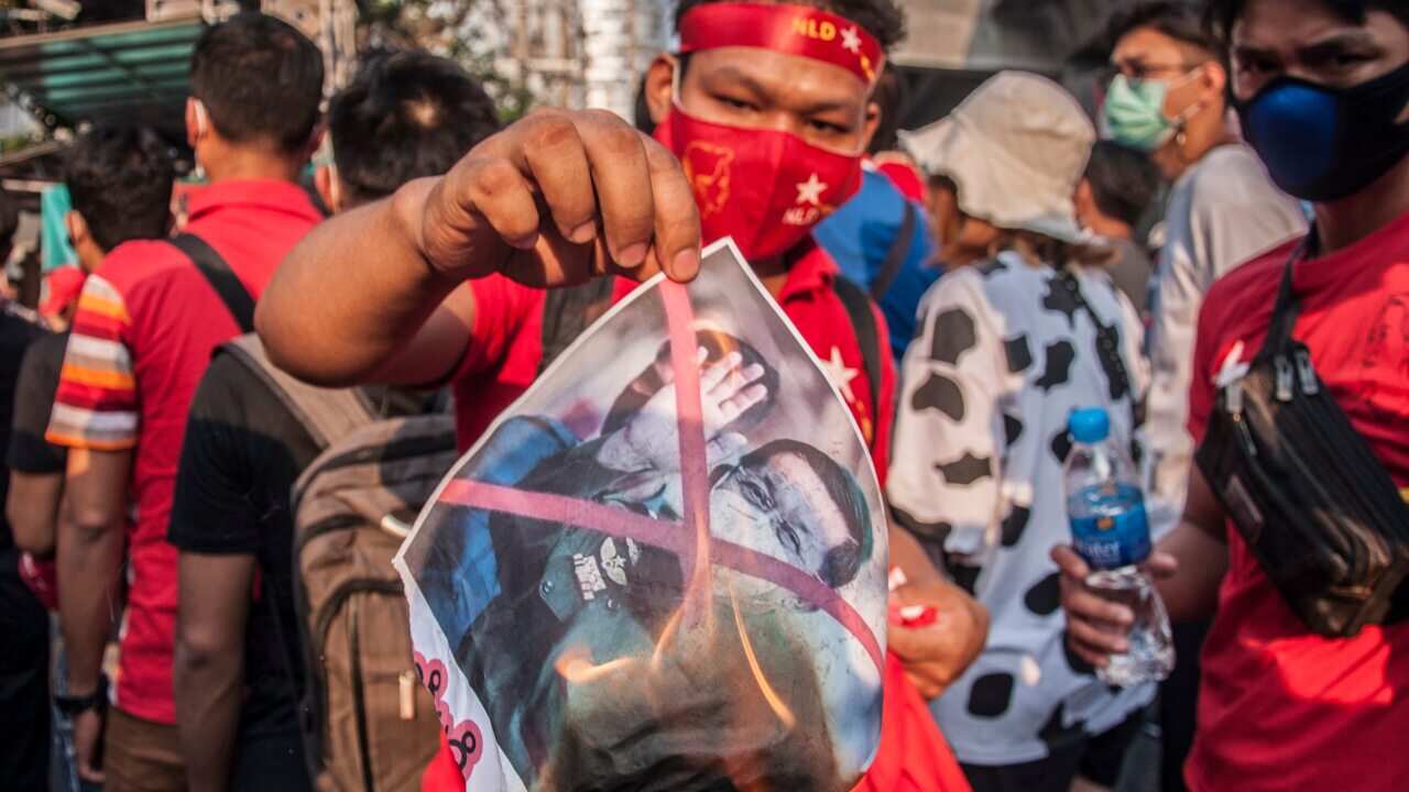 A National League for Democracy (NLD) supporter holds a burning portrait of Myanmar's army chief Min Aung Hlaing during a demonstration in Bangkok on 2 January.