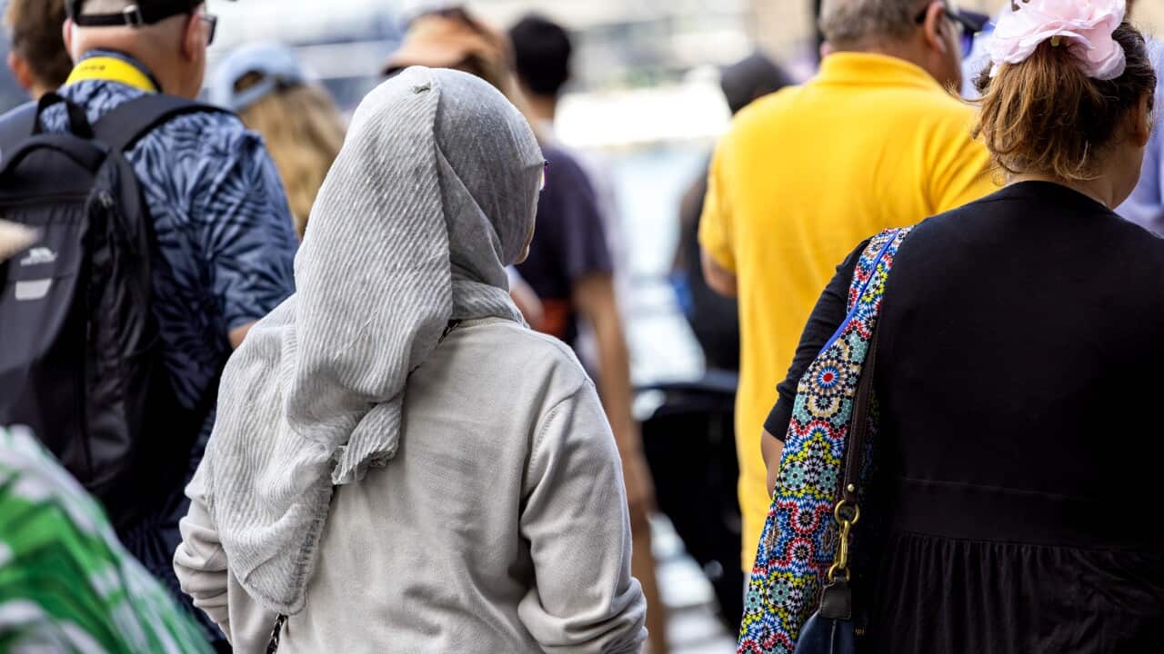 Rear view of woman wearing hijab walking in crowd of people, background with copy space