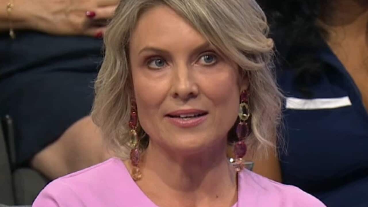 A woman speaking while seated in an audience.