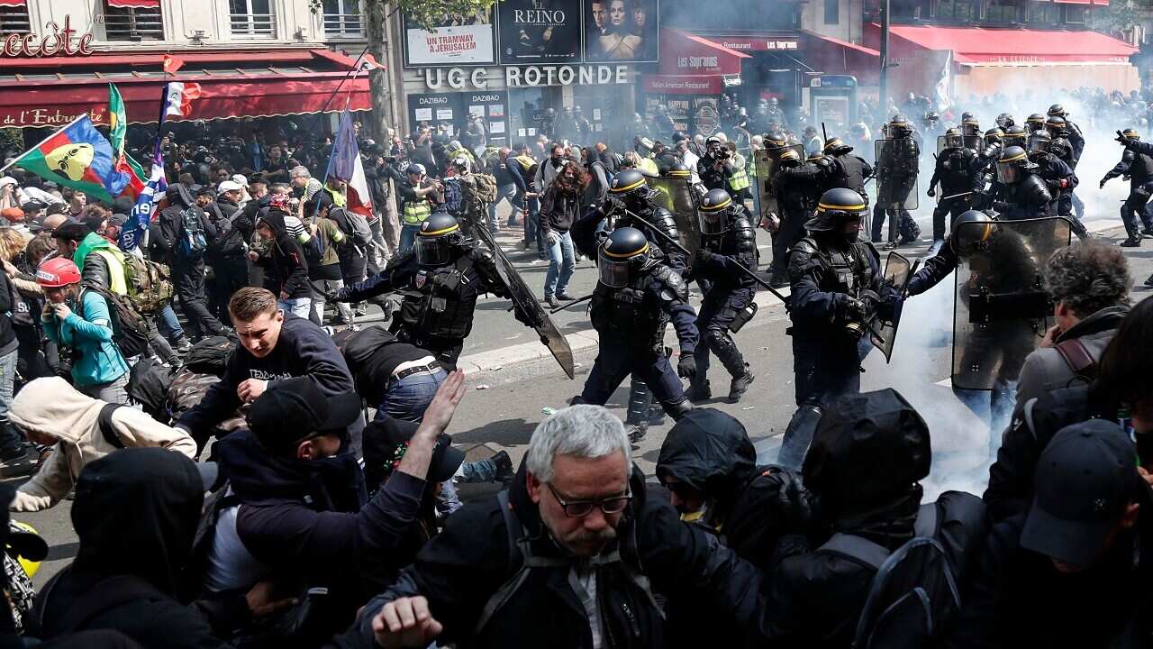 Riot police officers and protesters clash in Paris.