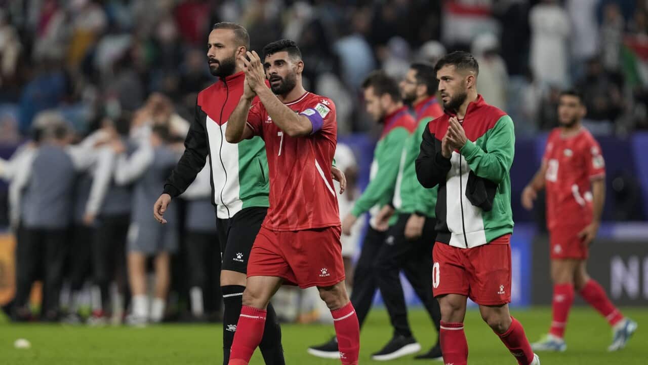 Members of the Palestinian team clap their hands in thanks and acknowledgment of supporters in the crowd.