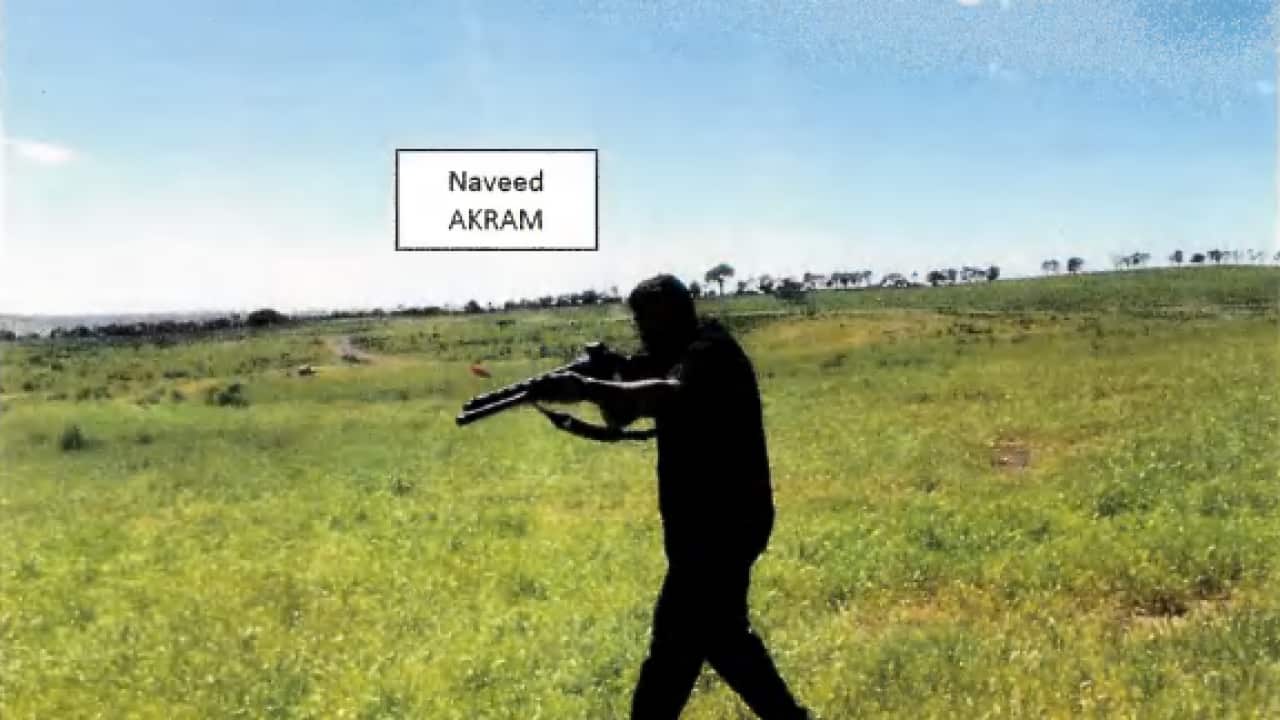 A man holding a long-arm firearm in a paddock