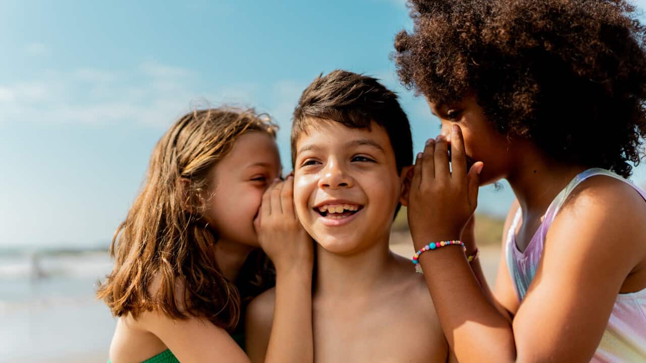Child girls telling a gossip to a friend on the beach