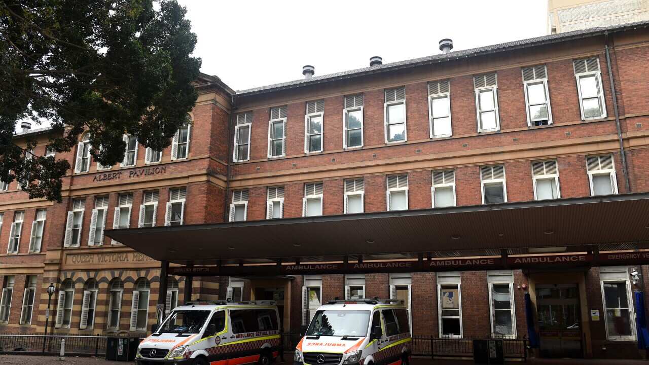 Brick hospital building with two ambulances parked outside the emergency entrance.